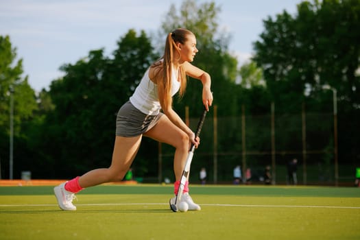 girl hockey player plays field hockey on a sunny day, female hockey player hits the ball with a stick, field hockey concept
