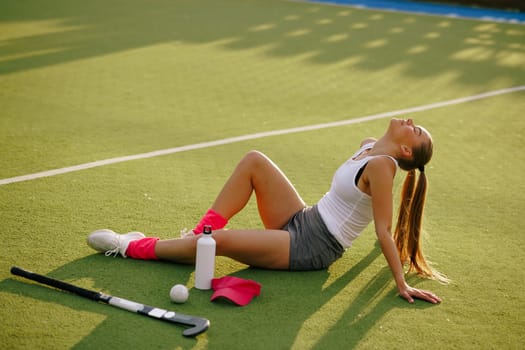 girl hockey player plays field hockey on a sunny day, hockey player drinks water during a break in the match, active sport for girls