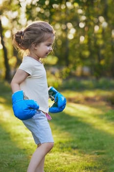 Charming child doing boxing in the backyard on the Sunset.