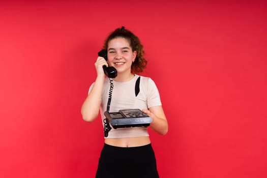 Portrait of pretty person arms hold vintage handset doubtful face isolated on a red color background