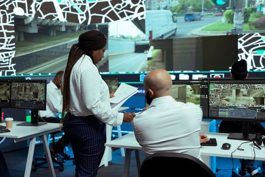 African american manager provides essential awb and receipt for logistics work, proceeding with order tracking on satellite navigation. Supervisor overseeing cargo transportation activity.