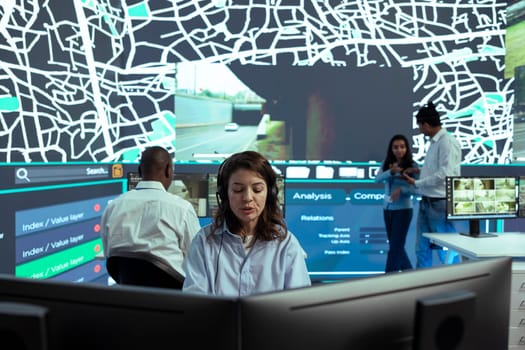 Female employee operates on satellite map CCTV radar to monitor delivery trucks and cargo, ensuring express shipping service. Dispatcher uses global positioning system to locate couriers.