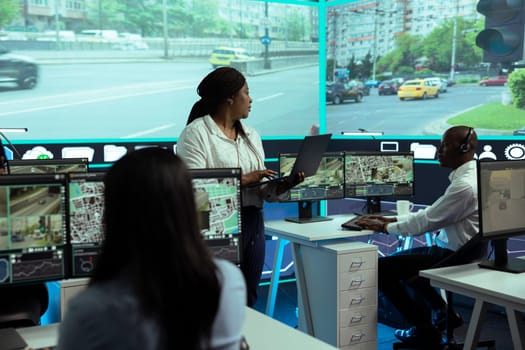 Diverse employees monitoring urban traffic in control center agency, following cars and their license plate data through video surveillance and CCTV networks. Government radar sensors.