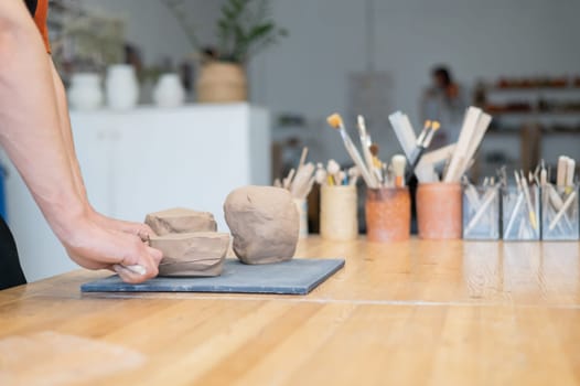 A potter cuts a piece of clay into pieces before using it in the workshop