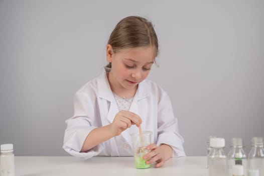 Caucasian girl doing chemical experiments on a white background. Making slime