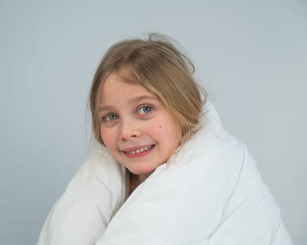 Portrait of a cute little girl wrapped in a white blanket