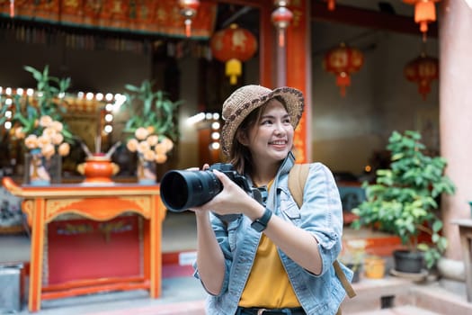 A joyful woman traveler with a camera, exploring vibrant cultural landmarks, ready to capture and cherish her travel experiences.