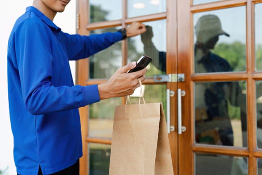 Delivery service worker knocking on a door, holding a paper bag and smartphone, representing modern home delivery for online shopping and food orders.