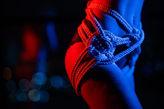 Close-up of a woman's belly in ropes tied using the Japanese shibari technique