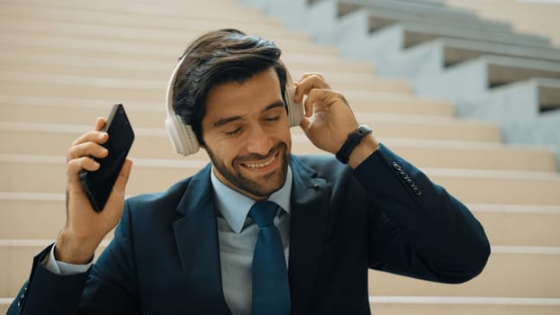 Closeup of smart business man listening and enjoy music while wear headphone. Project manager smiling while getting good news, getting promotion, increasing sales. Relaxing man enjoy music. Exultant.