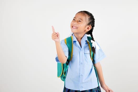 Portrait smiling Asian little girl kindergarten with schoolbag pointing finger at copy space studio shot isolated white background, happy woman kid in pigtails wearing school uniform, back to school