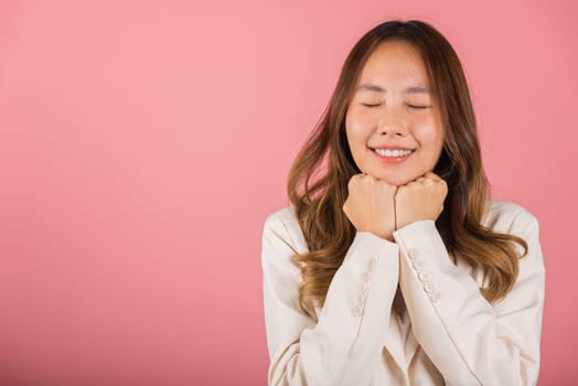 Asian happy portrait beautiful young woman standing smiling surprised excited her keeps hands pressed together under the chin studio shot on pink background with copy space for text