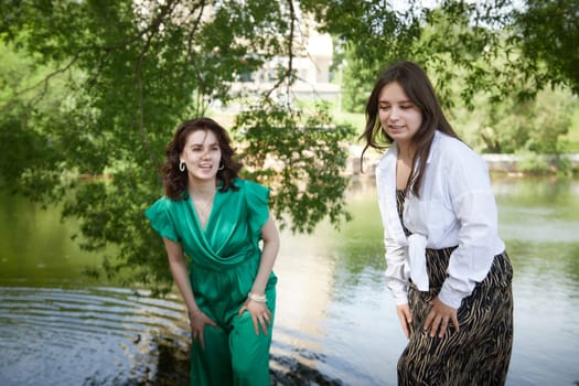 Portrait of happy girls in the park in summer. Female friends together. Young women pose in sunny park during summer, enjoying time outdoors