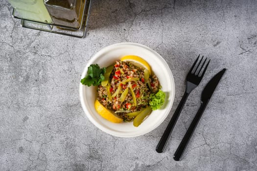 Quinoa salad on a white styrofoam plate on a stone table