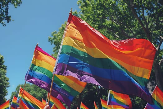 A group of people holding rainbow flags in the air. The flags are of different sizes and colors, and they are all held up high. Concept of unity and pride