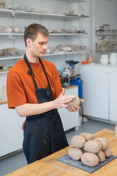 Potter kneads clay before using it in the workshop. Vertical photo