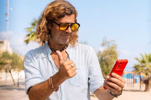 Caucasian man wearing sunglasses feeling smiling showing his finger up in approval outdoors.