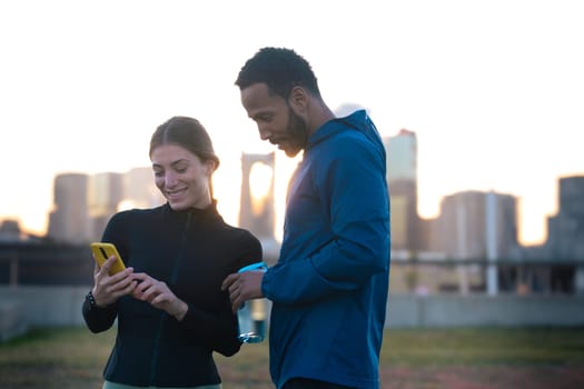 Young couple using a social media app on smartphone while exercising outdoors.