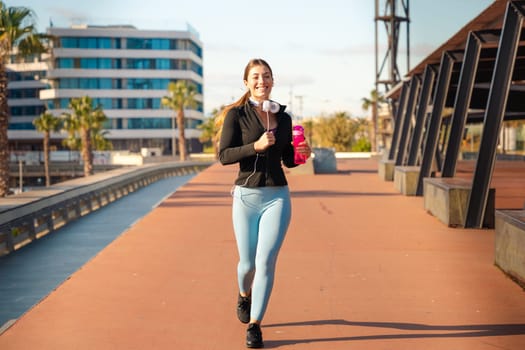 Fitness girl is running outdoors. Concept of workouts and healthy lifestyle.