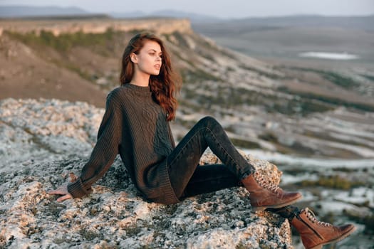 Serene woman sitting crosslegged on rock with majestic mountain range in background