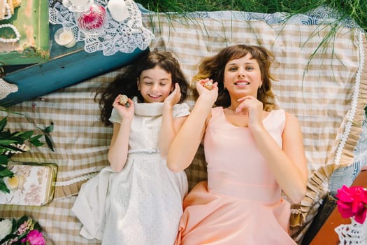 happy mother and daughter playing and smiling while lying on a blanket in the Park in the summer