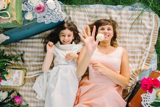 happy mother and daughter playing and smiling while lying on a blanket in the Park in the summer