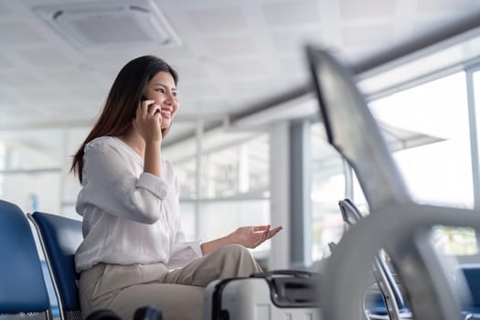 Professional businesswoman at airport terminal, talking on phone, ready for travel. Modern business travel concept with luggage in airport lounge.