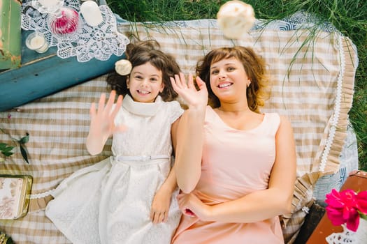 happy mother and daughter playing and smiling while lying on a blanket in the Park in the summer