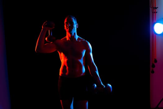 Adult muscular man smiling and screaming while working out hard with a dumbbells.