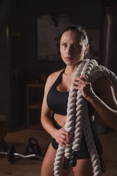 Caucasian woman posing with ropes in retro gym