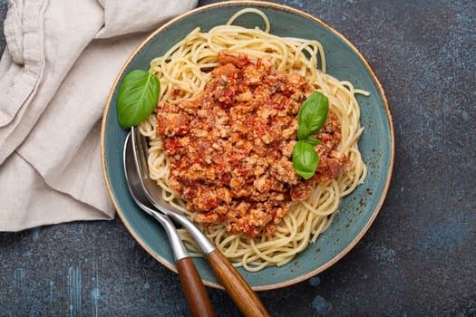 Steaming plate of spaghetti topped with a hearty bolognese sauce, garnished with fresh basil leaves, is ready to be enjoyed