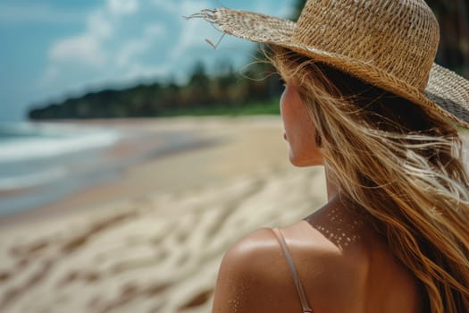 Woman in a straw hat standing on the beach gazing at the sea and ocean beauty and serenity