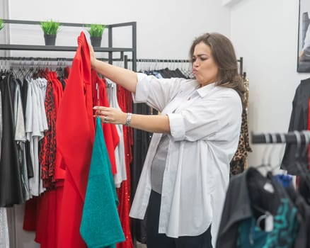 A fat woman chooses clothes in a plus size store