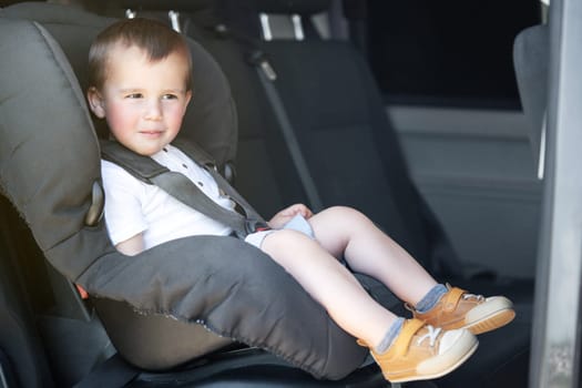 Toddler sitting in a car seat inside the car. Transportation and safety. 