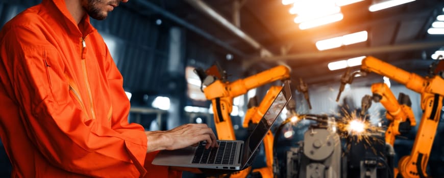 MLP Engineer use advanced robotic software to control industry robot arm in factory. Automation manufacturing process controlled by specialist using IOT software connected to internet network.