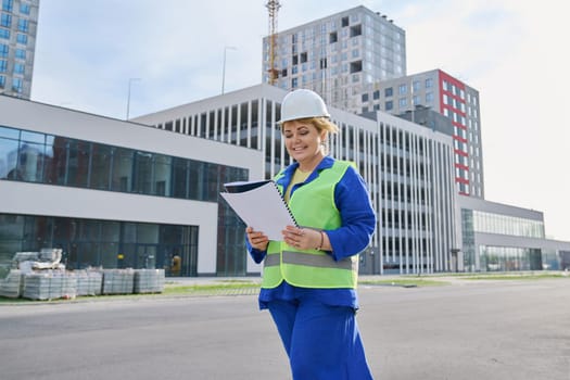 Confident mature female engineer developer architect inspector at construction site, outdoor development of residential complex. Construction industry service development work concept