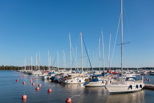 Marina sea port, sailboats moored at the dock and reflected in the sea, harbor, sea and blue sky, sunny day in Finland