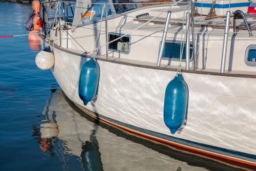 Docked boat with blue fenders hanging alongside vessel, sunny summer, sailboat, yacht protection in Finland