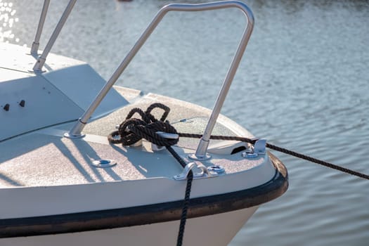 Black rope tied to the mooring cleat of a sailboat, sunny light, Finland