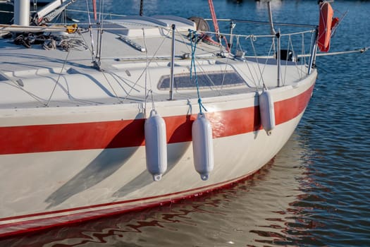 Docked boat with white fenders hanging alongside vessel, sunny summer, sailboat, yacht protection in Finland