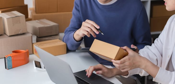 Couple running a small online business, packing products for shipping. E-commerce entrepreneurs working together from home.