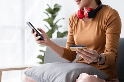 Woman using smartphone to shop online and paying with a credit card. Modern lifestyle and digital payment concept.