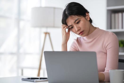 Young woman feeling stressed at work, overwhelmed by tasks, and experiencing workplace anxiety in a modern office setting.