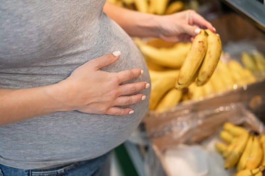 Pregnant woman buys bananas in the store