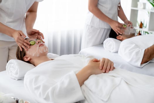 Serene daylight ambiance of spa salon, couple customer indulges in rejuvenating with luxurious cucumber facial mask. Facial skincare treatment and beauty care concept. Quiescent