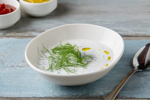 Turkish Cacik or tzatziki (caciki) on white porcelain plate on wooden table