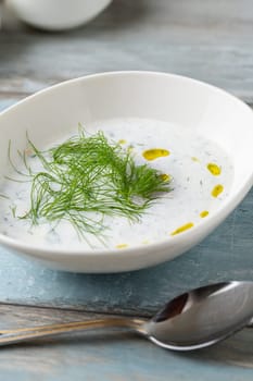 Turkish Cacik or tzatziki (caciki) on white porcelain plate on wooden table