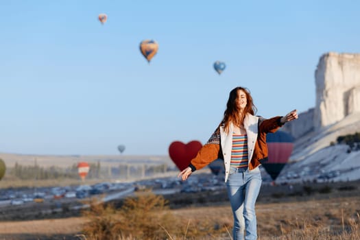 Woman admiring colorful hot air balloons against majestic mountain backdrop