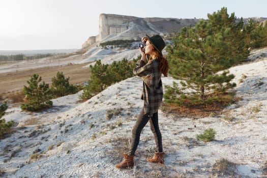 Woman in plaid shirt standing on hill gazes at distant view on sunny day