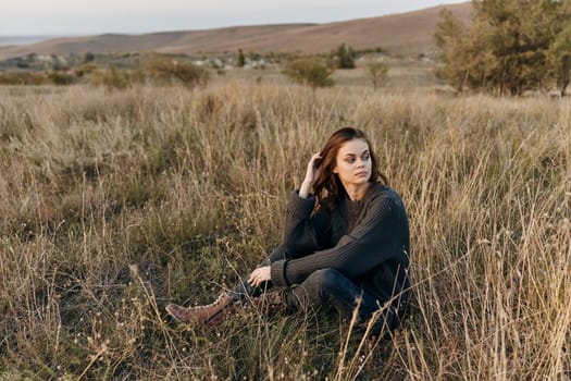 Woman feeling overwhelmed sitting in a sunny field with hands on head in distress